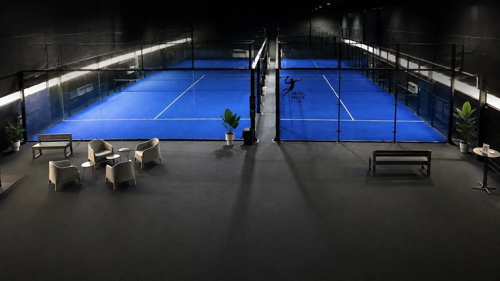 Die Padelhalle des Padel Move Club: zwei blaue Indoor-Courts mit Glaswänden und Lounge-Bereich